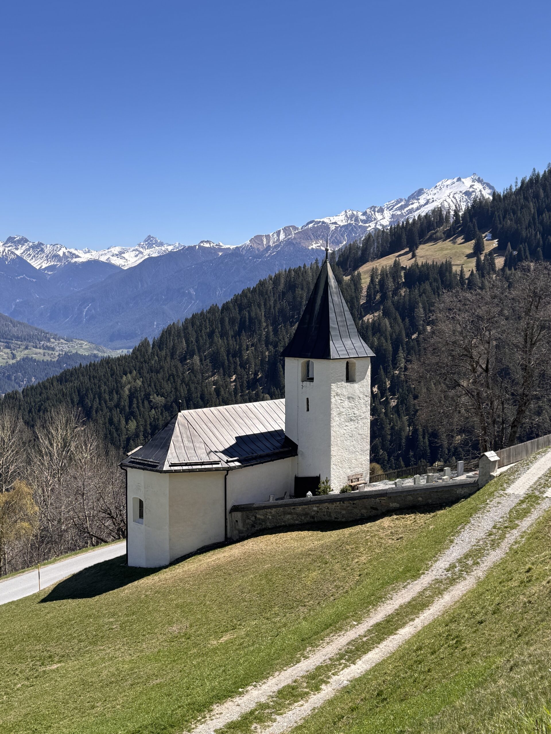 Kirche Mutten von oben, im Hintergrund Blick ins Tal und auf die umliegenden Berge